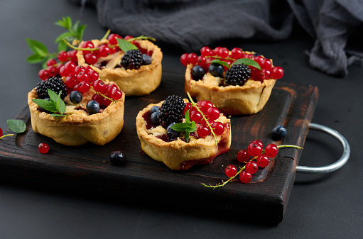 Round mini fruit pie on a wooden board, close up