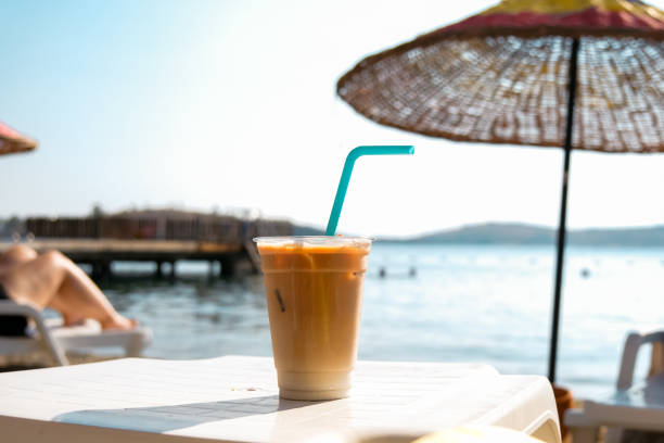 istock Ice latte coffee in plastic glass on the beach. 1421410784