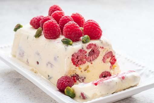 semifreddo, italian ice cream dessert, with raspberry and pistachios