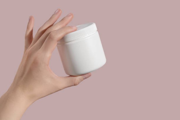 istock Hand holding blank white plastic supplement container on pink background. Package mockup blank for capsule. 1421415839