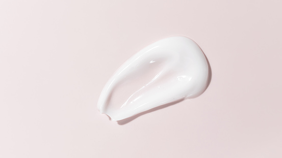 Mancha de crema de belleza blanca sobre fondo rosa. Textura cosmética del producto para el cuidado de la piel. Crema facial, loción corporal swipe swatch photo