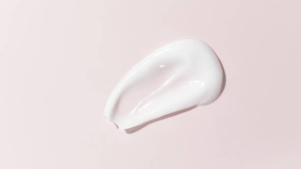 mancha de crema de belleza blanca sobre fondo rosa. textura cosmética del producto para el cuidado de la piel. crema facial, loción corporal swipe swatch - facial cleanser fotografías e imágenes de stock