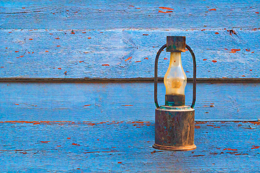 old rusty kerosene lamp in a blue wooden wall