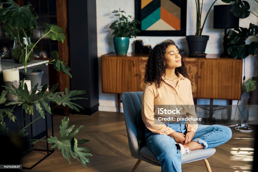 Peace, relax and happy mindset of a woman from Indonesia taking a mind and meditation home break. Happiness of woman on a house living room lounge chair thinking about life, gratitude and self care Relaxation Stock Photo