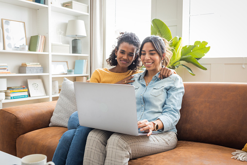 Lesbian couple enjoying shopping online while relaxing together in their living room at home.