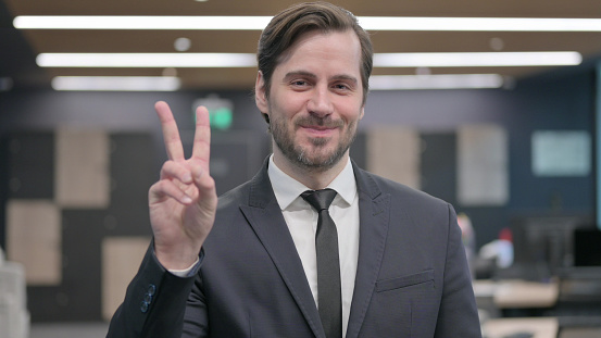 Portrait of Young Businessman showing Victory Sign with Finger