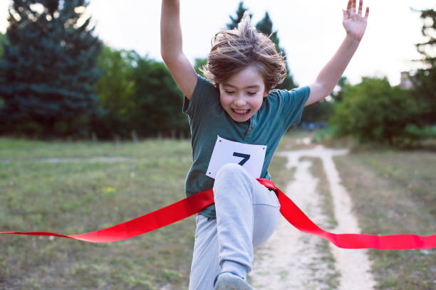 Little child runner crossing finish line in a race competition stock photo