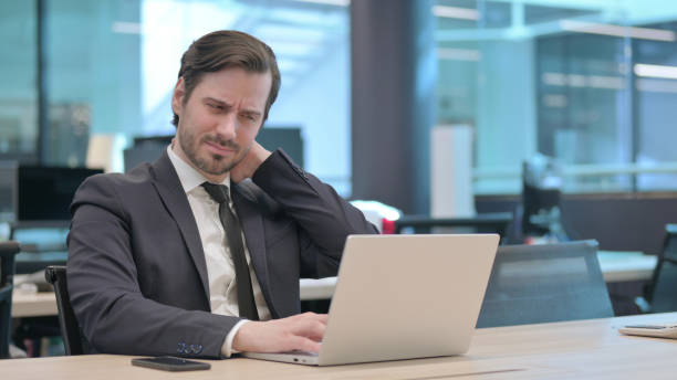 istock Businessman having Neck Pain while using Laptop in Office 1421431564