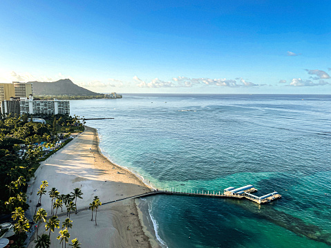 Areal view of the quiet sandy beaches and clear waters of Waikiki, as the first rays of early morning sun arrive