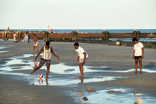 Ocean City, USA - September 3, 2022. Black young men playing soccer on beach at Ocean City, New Jersey, USA