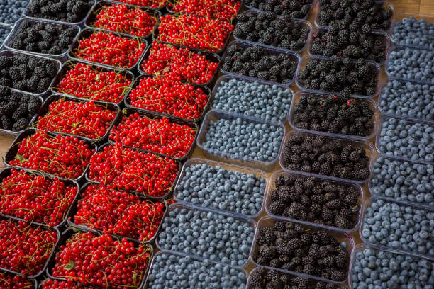 Fresh strawberries, raspberries, blackberries on the counter, ripe berries in plastic containers on the counter in the supermarket