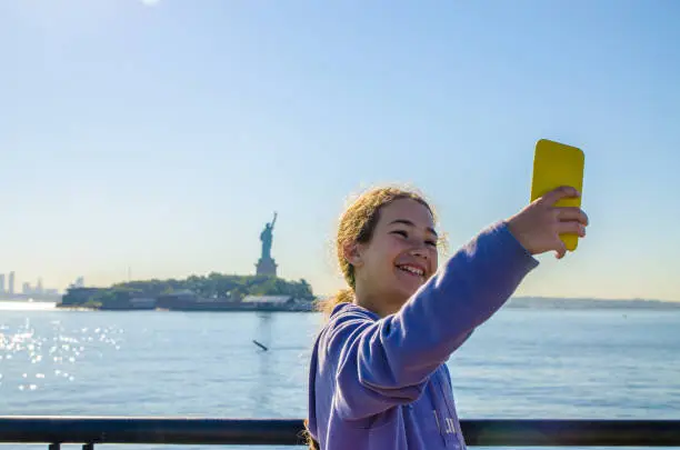 Photo of Teenage girl taking selfie with Statue of Liberty from Liberty State Park