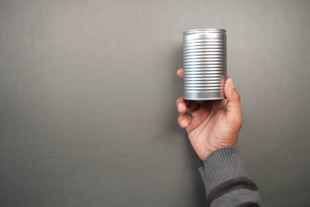 istock man holding a canned food on black background 1421436771