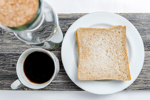 Sliced bread and a cup of coffee on the board isolated over white background