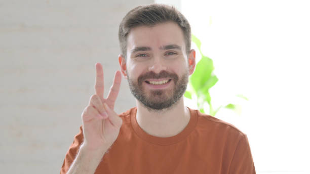 istock Young Man Showing Victory Sign with Finger 1421448421