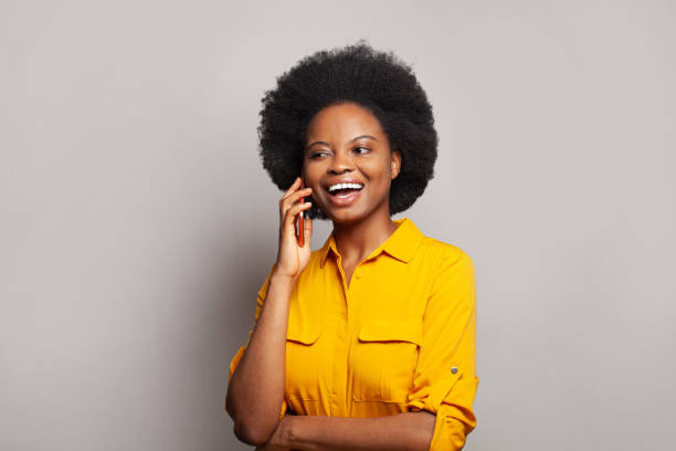 istock Pretty black woman laughing while talking by smartphone 1421449568