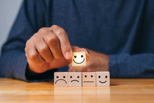 istock Top Smile Satisfaction. Best excellent business services rating customer experience. Satisfaction survey concept. Hand of a businessman chooses a smiley face on wood block cube. 1421453605