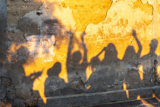 istock Shadows of dancing people on an old stone wall at sunset time. 1421453943