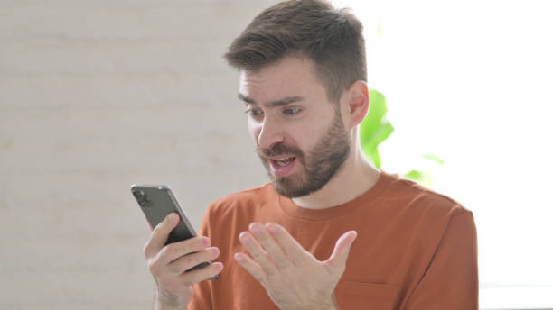 istock Young Man Reacting to Loss on Smartphone 1421454234