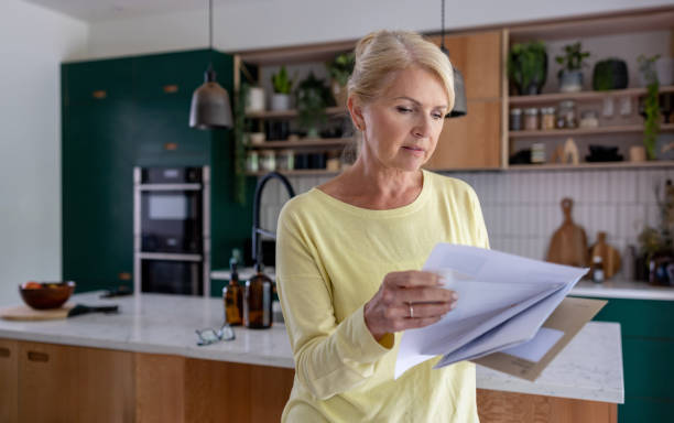istock Woman at home reading a letter in the mail 1421456308