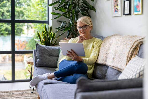 istock Senior woman at home reading on a tablet computer 1421456309