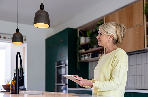 Senior woman at home controlling the lights using an automated system - smart home concepts