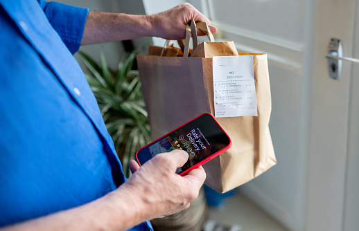 Close-up on a man rating his experience on the app after ordering food to his house â technology concepts