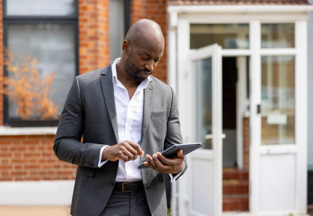 istock Real estate agent at a house for sale and using his tablet 1421456330