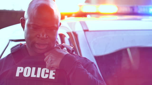 African-American policeman on radio, lights flashing