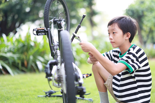 Child boy repair bicycle outdoors