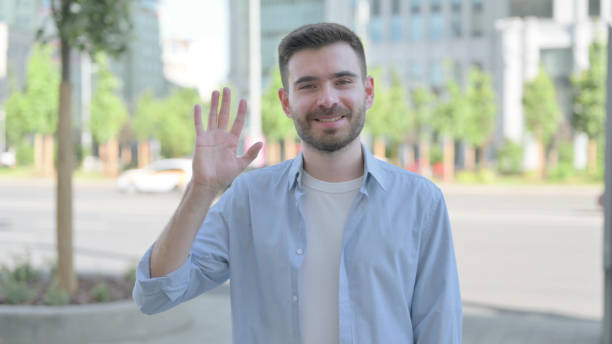 istock Welcoming Young Man Waving Hand for Hello Outdoor 1421471359