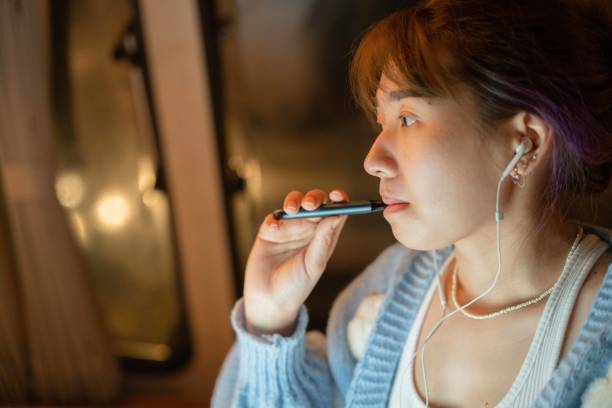 istock Attractive woman holding an e-cigarette 1421472376