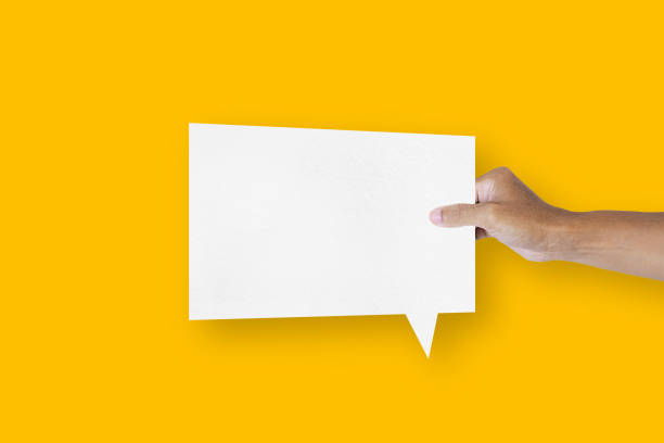 istock hand holding a square shaped white paper balloons speech bubbles isolated on yellow background communication bubbles 1421483986