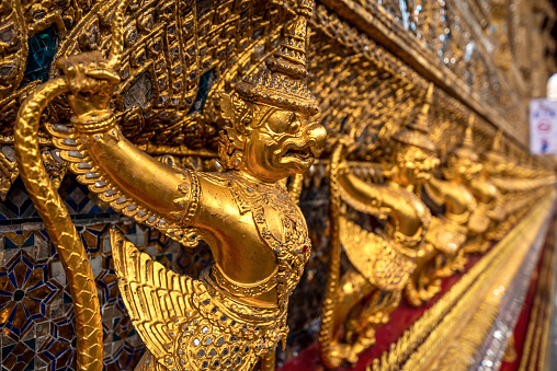 Golden garuda and naga statue, decoration on a wall of The Emerald Buddha temple, Wat Phra Kaew, Grand Palace, Bangkok, Thailand