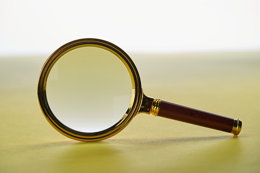 close up of magnifying glass against yellow background