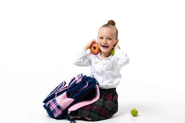 Cute girl in school uniform fooling around collecting a backpack to school Isolated on a white background.