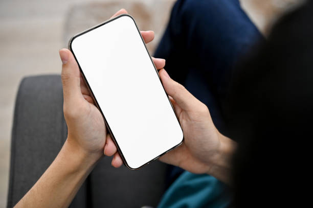 istock close-up, A man using his smartphone, holding a mobile phone white screen mockup. 1421488643