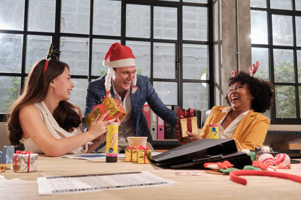 Male boss giving gifts to coworkers at office in Christmas festival party. stock photo