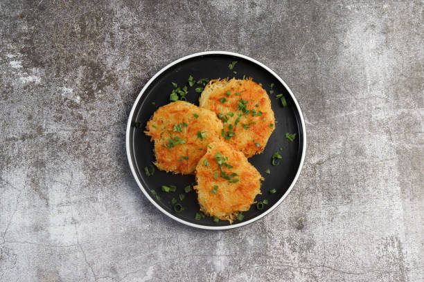 Rustic hash browns with chives on a round plate on a dark background. Top view, flat lay Rustic hash browns with chives on a round plate on a dark background. Top view, flat lay hash brown stock pictures, royalty-free photos & images