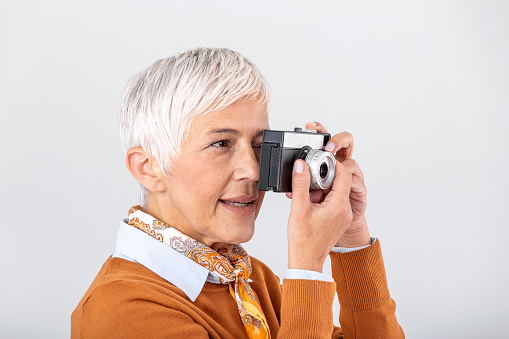 Mature female photographer taking pictures with old retro camera. Professional photographer doing a photoshoot.