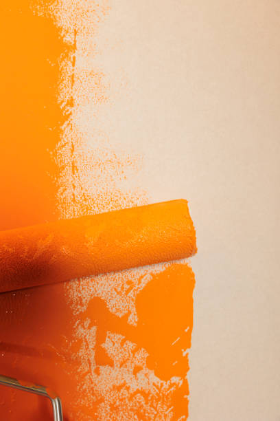 istock Rolling brush with orange paint to renovate 1421496964