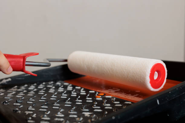 istock Mother using paintbrush roll and orange color 1421497448