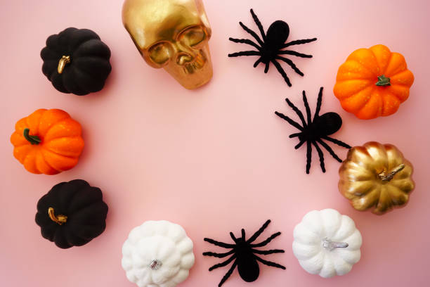 bunte kürbisse, ein goldener totenkopf und schwarze spinnen liegen auf rosa grund - miniature pumpkin stock-fotos und bilder