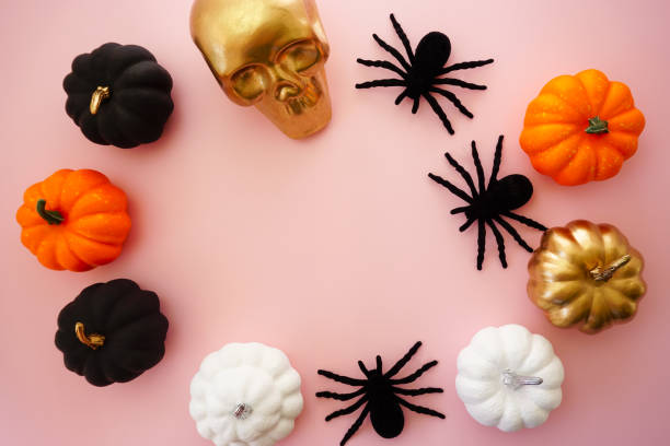 Multicolored pumpkins, a golden skull and black spiders lie on a pink background Multicolored pumpkins, a golden skull and black spiders lie on a pink background miniature pumpkin stock pictures, royalty-free photos & images