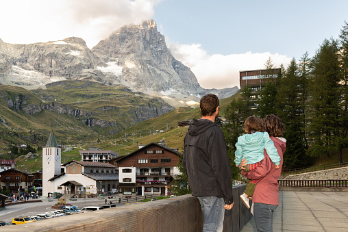 Rear view of a family with one toddler looking at Matterhorn since Cervinia in Italian Alps. Family travel.