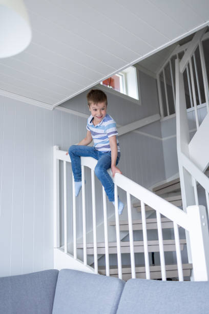 istock Boy sliding on the staircase in the house 1421511837