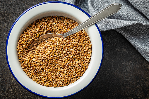 Uncooked buckwheat grain in bowl. Top view.