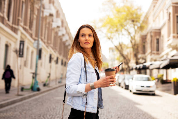 istock Happy woman using the phone while walking on the street 1421514818