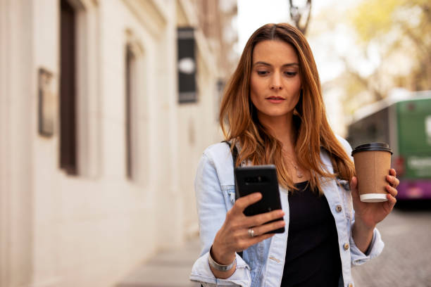 istock Happy woman using the phone while walking on the street 1421514826