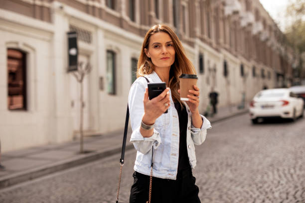 istock Happy woman using the phone while walking on the street 1421514901